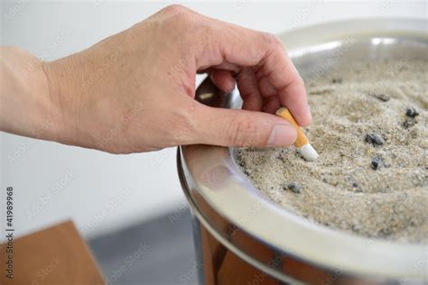 Male Hand Stubbing Out Cigarette In Sand Ashtray Bin Stock Photo