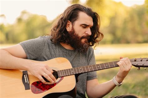 Close Up Shot Of A Handsome Bearded Man Playing Guitar While Sitting In