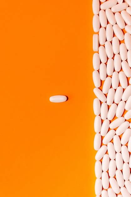 Premium Photo White Pills On Orange Surface