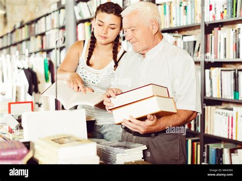 Grandfather With Granddaughter Are Reading Books In Bookstore Stock