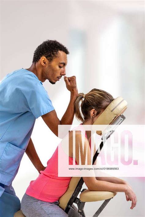 Physiotherapist Giving Back Massage To A Patient Sitting In A Massage Chair In The Clinic