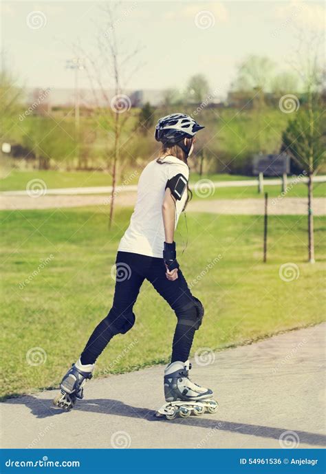 Menina Da Patinagem De Rolo No Parque Que Rollerblading Em Patins