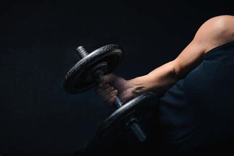 Premium Photo Midsection Of Woman Lifting Dumbbell In Darkroom