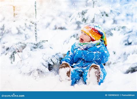 Baby Playing With Snow In Winter Child In Snowy Park Stock Photo