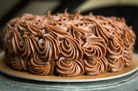 A Chocolate Frosted Cake Sitting On Top Of A Wooden Table