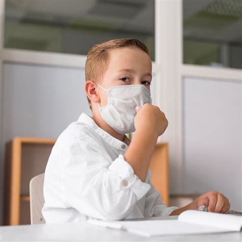 Criança usando uma máscara médica na sala de aula Foto Grátis