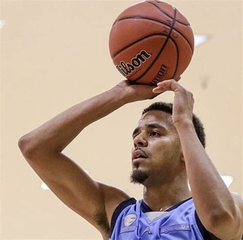 A Man Holding A Basketball In His Right Hand And Looking Up At The Ball