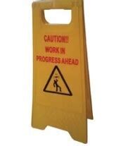 Yellow warning shaped sign printed ,"CAUTION WORK IN PROGRESS OVERHEAD ...