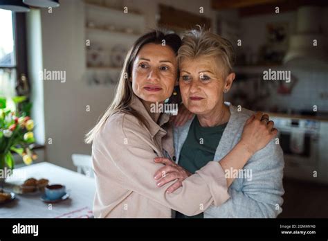 Portrait Of Senior Mother Hugging With Adult Daughter Indoors At Home