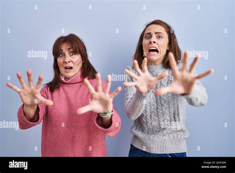 Mother And Daughter Standing Over Blue Background Afraid And Terrified