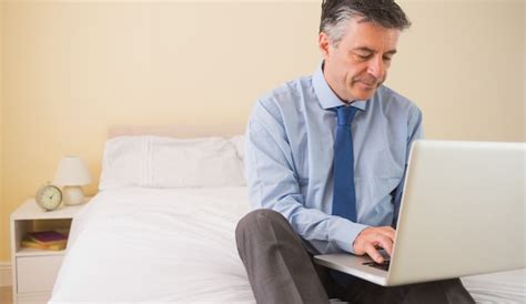 Homem Concentrado Usando Um Laptop Sentado Em Uma Cama Foto Premium