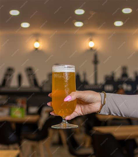 Premium Photo Womans Hand Holding Glass Of Beer Up High In Restaurant