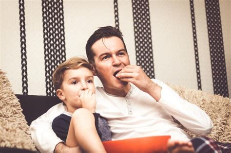 Padre e hijo viendo la televisión mientras están sentados en el sofá