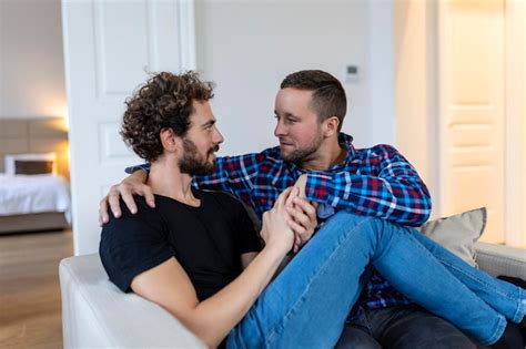 Pareja gay guapo acostado en la cama juntos romántica pareja gay joven abrazándose cariñosamente