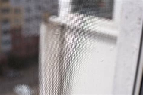 A Mosquito Net On The Balcony Door And Legs Of A Woman Sitting In The