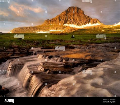 Waterfall Along Reynolds Creek At Logan Pass With Mt Reynolds And Snow Bank At Sunrise Glacier