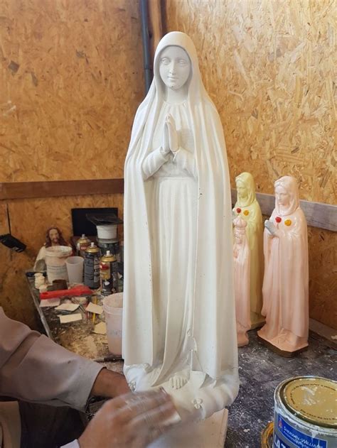 A Statue Of The Virgin Mary Is Being Worked On By A Man In A Workshop