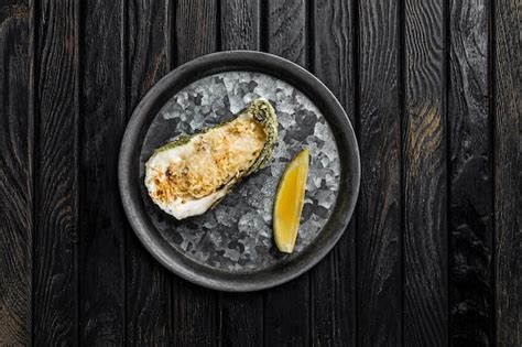 Premium Photo | Oyster baked with cheese served with lemon on a rustic metallic plate shot on ...