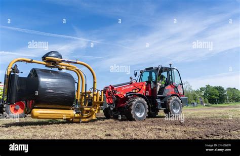 Wrapping Big Bales Of Silage With An Attachment On The Front Of A