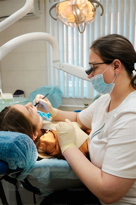 A Woman Getting Her Teeth Checked By A Dentist Photo Dentist Image On Unsplash