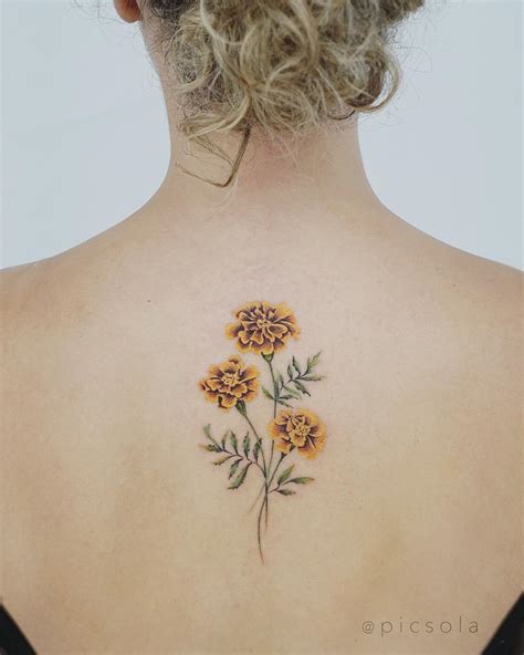 Marigold tattoo on the back by tattooist picsola - Tattoogrid.net