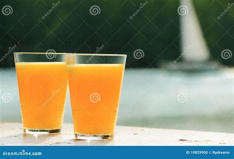 Dois Vidros Do Sumo De Laranja De Encontro Ao Mar Foto De Stock