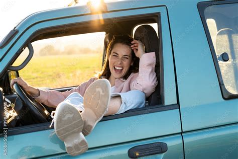 Carefree Young Woman Relaxing While Sitting With Feet Up On Car Window During Road Trip Stock