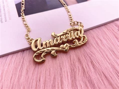 A Gold Necklace With The Word Anniversary On It Sitting On Top Of A