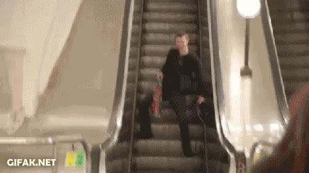 A Man Riding An Escalator With His Luggage