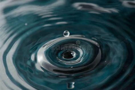 Closeup Of A Droplet Falling Into The Rippling Water Stock Photo