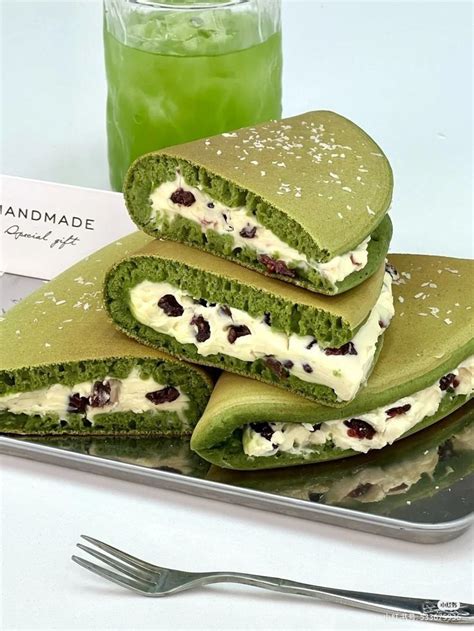 Green Pancakes With White Cream And Cranberries Are On A Plate Next To