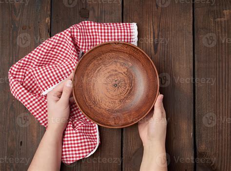 Two Female Hands Holding An Empty Round Clay Plate Stock Photo