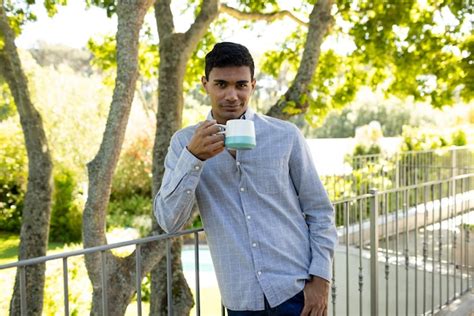 Premium Photo Portrait Of Happy Biracial Man Holding Mug On Balcony