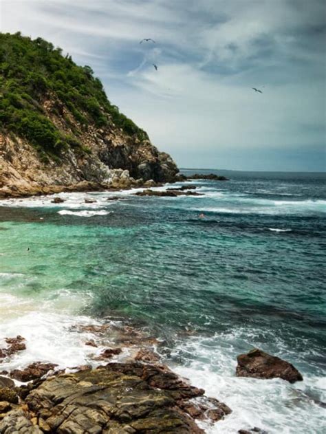 the beach is rocky and clear with waves crashing in front of it on a ...