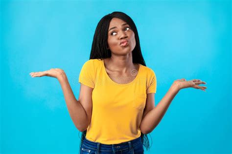 Thoughtful African Woman Holding Two Invisible Objects Over Blue