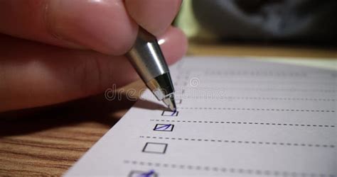 Closeup Of Hand Putting Checkmark Or Marking With Blue Pen On Checklist