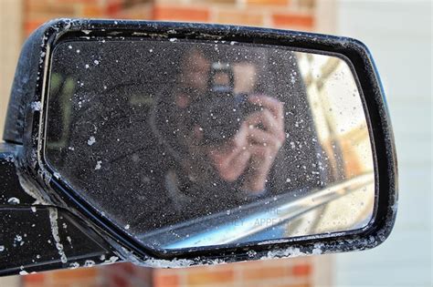 Reflexão de um homem fotografando no espelho lateral de um carro Foto