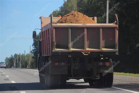 Camión volquete cargado pesado con arena en una carretera suburbana en