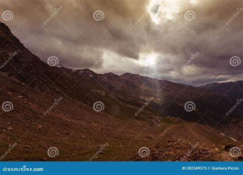 Bright Sunlight Shining Through Hole Of Clouds To Scene Of Alpine