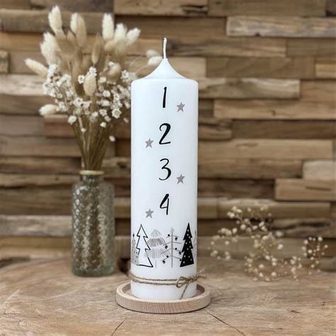 A White Pillar With Numbers And Trees On It Next To A Vase Filled With