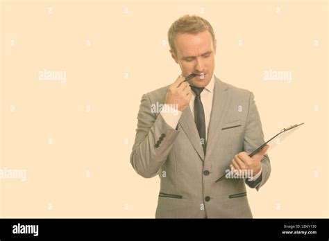 Handsome Caucasian Businessman Thinking While Biting Pen And Reading