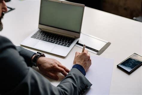 Man Writing Down on Paper by Laptop · Free Stock Photo