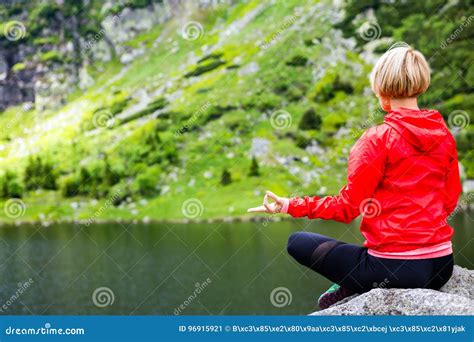 Mulher Que Medita Na Pose Da Ioga Na Frente Do Lago Da Montanha Imagem