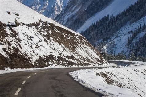 A Curvy Winding Road Passing Through Snow Covered Mountains Of