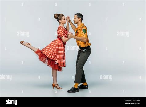 Cheerful Dancers Holding Hands While Dancing Boogie Woogie On Grey