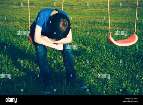 Sad lonely boy sitting on swing alone Stock Photo - Alamy