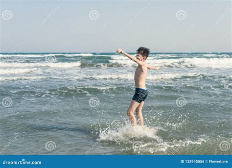 El Muchacho Que Salta En Ondas Del Mar Con Agua Salpica Concepto Foto