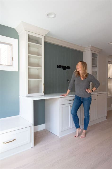 A Woman Standing In The Middle Of A Kitchen Next To A Counter Top And