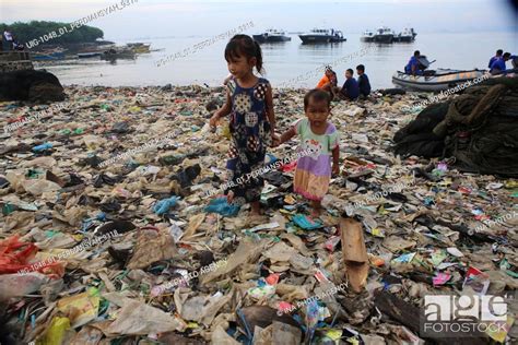 A child is seen playing on a pile of plastic garbage. Lampung Regional Police, Stock Photo ...