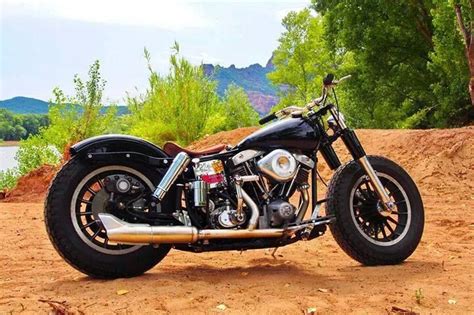 A Black Motorcycle Parked On Top Of A Dirt Field Next To A Lake And Trees